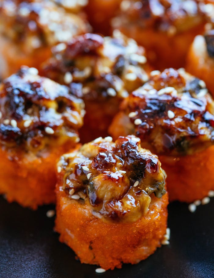 Close-up of delicious baked sushi rolls with a savory glaze, perfect for food lovers.